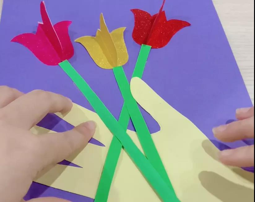 步骤6：用绿色卡纸剪成长条形贴在花朵的下面放在手上，此时你可以调整手的位置。