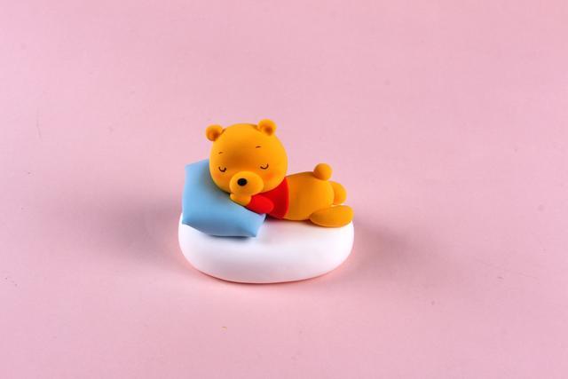 步骤9：用橘黄色粘土做出维尼熊的双腿，这样睡觉的小熊维尼就做好啦！