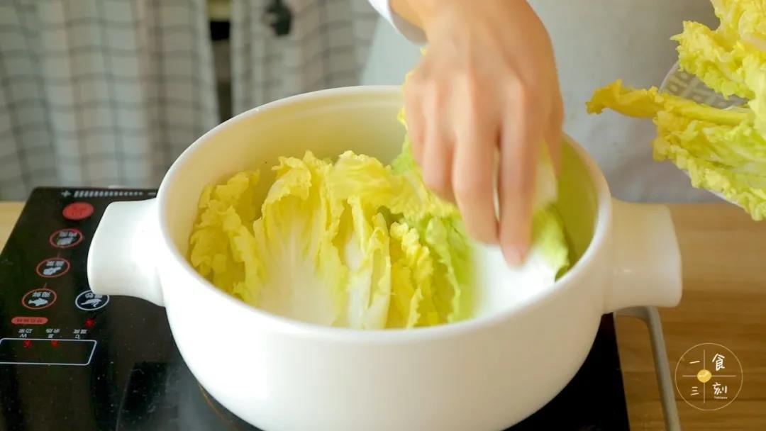 砂锅中，放入少量油、娃娃菜和金针菇垫底