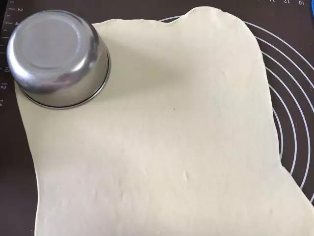 将面团擀成大饼状，拿个圆碗倒扣压出圆形。