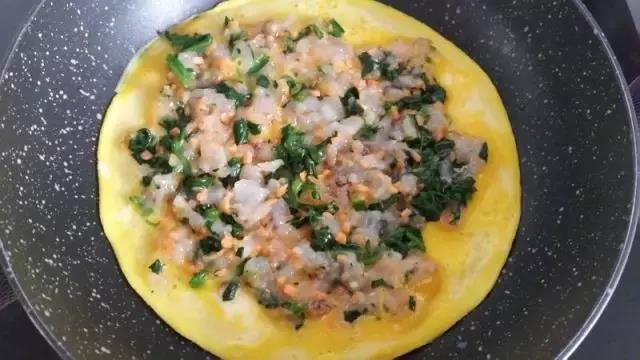 蛋液半熟时铺上虾和蔬菜。