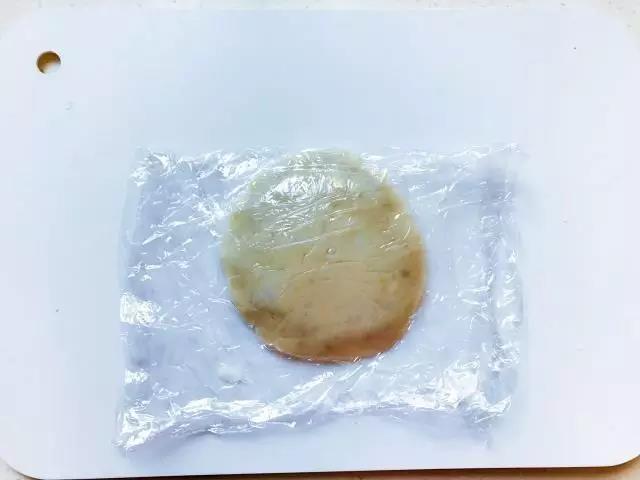 第6步：上面再铺上一个圆饼，然后在保鲜膜里面压实，把饼的边捏紧。