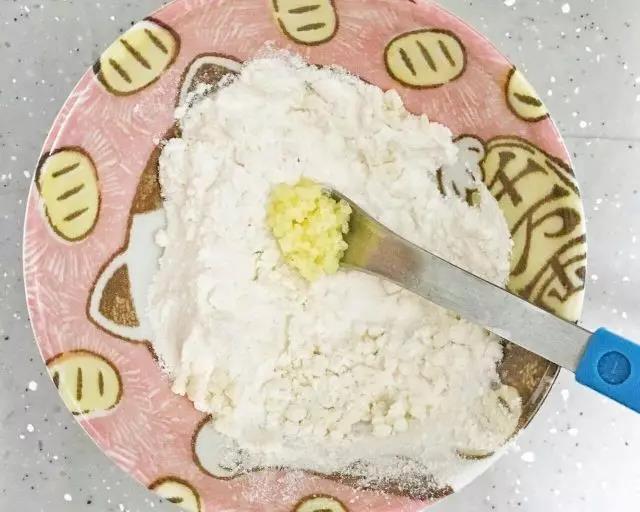 第3步：挖一勺小米放入面粉里顺时针搅拌，让小米粒完全裹上面粉。