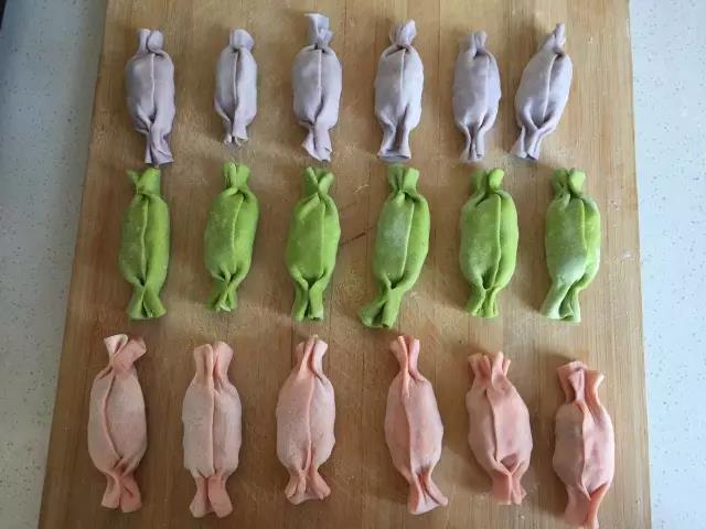 剩余的两边分别捏住收口，捏成糖果状，其他颜色的面皮也一样操作，饺子全部包好，水开后上锅蒸15分钟即可。