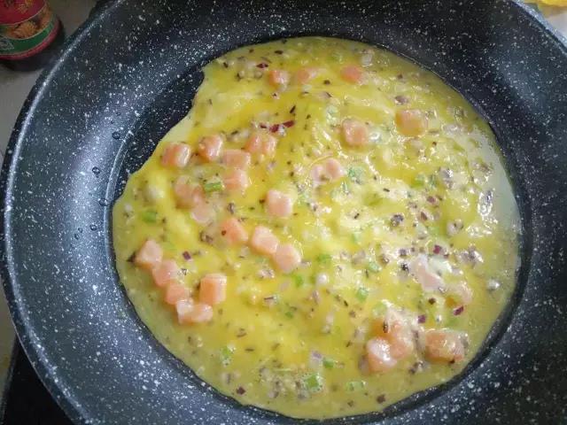 热锅少油，舀入三分之一蛋液，摊平至蛋液稍凝固。