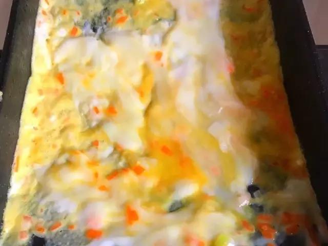 第5步：倒入1/3的鸡蛋液，转动平底锅让蛋液均匀的平铺在锅底。