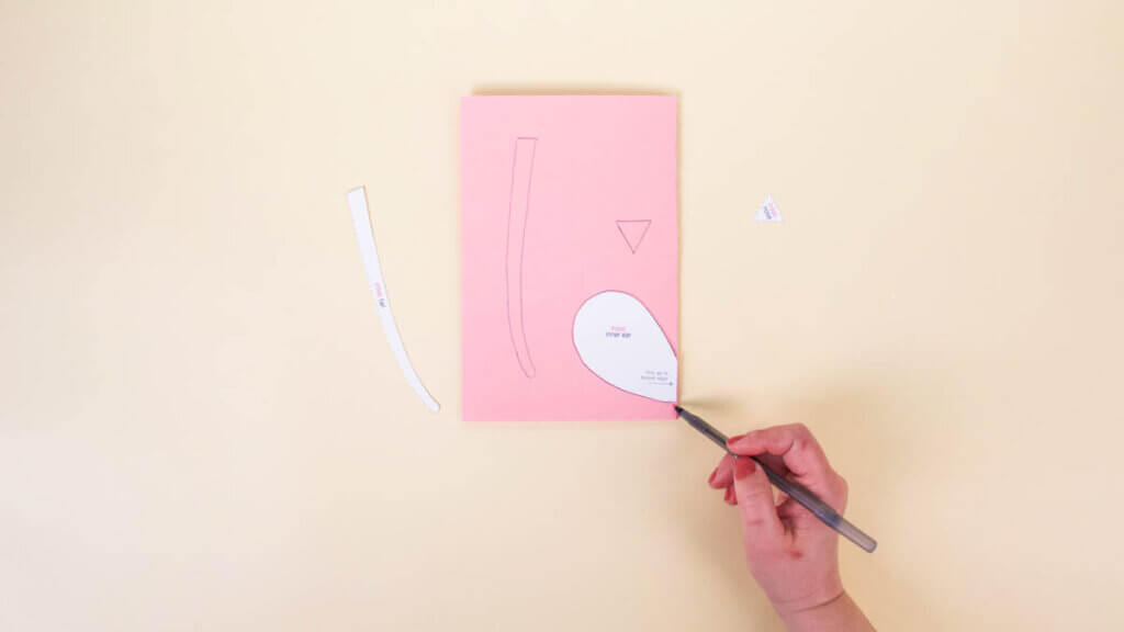 步骤6：将粉红色的纸对折。将内耳模板的边缘与折叠边缘对齐。