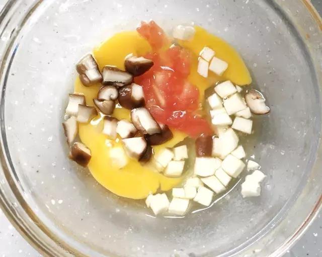 第3步：挖出的茄子取1/2的量切丁，番茄、香菇切丁，加蛋液混合打散。