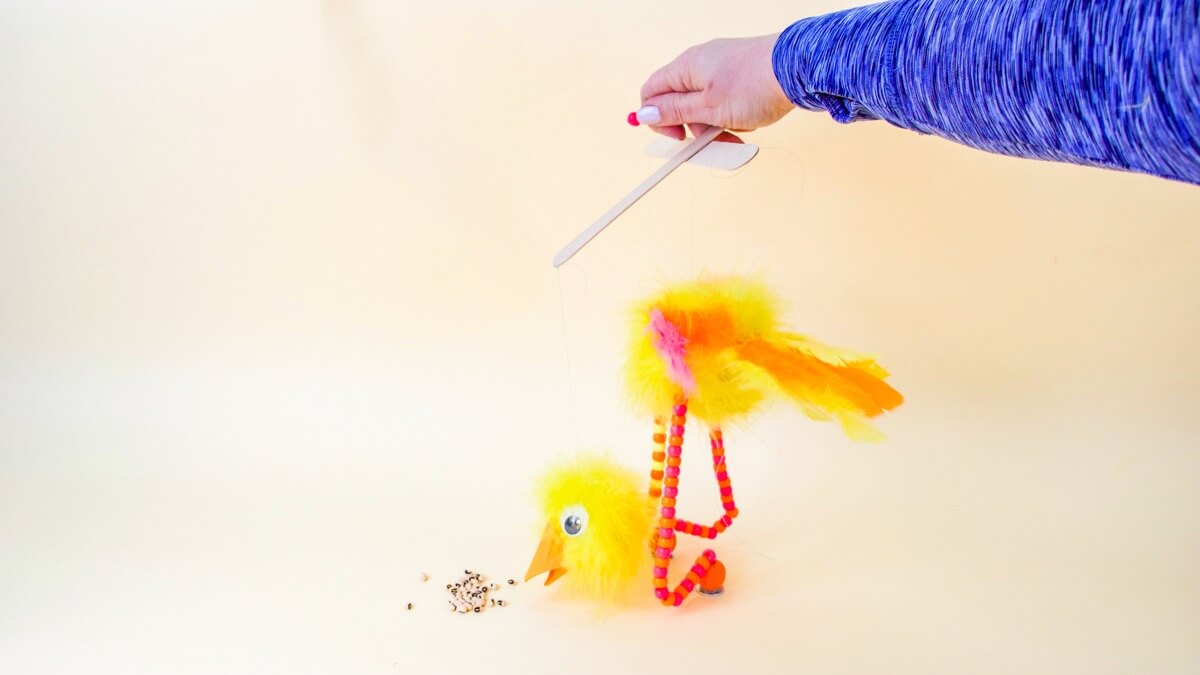 步骤12：将身体的第一条线穿过木偶操纵手柄的中心孔，找到所需的高度。将珠子系在绳子的末端。