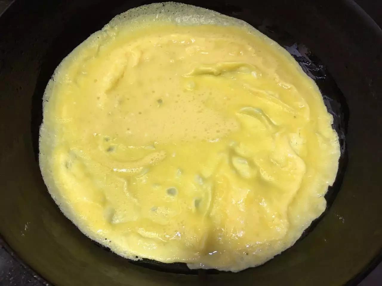 锅里刷入一层食用油，把调好的鸡蛋液倒入平底锅里，晃动锅，使鸡蛋液均匀铺在锅里。