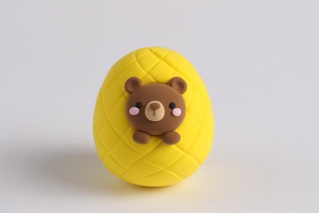 步骤5：黑色粘土做眼睛，淡黄色粘土和棕色粘土做好嘴巴部分，粉色粘土做腮红，还要揉两个棕色小圆球做小熊的胳膊，如图所示。