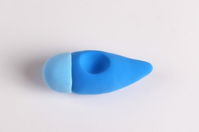 步骤2：用淡蓝色粘土做一个半球形粘在圆锥面的一端，然后用丸棒笔在圆锥体上部锤出一个小窝，这是飞机的驾驶舱。