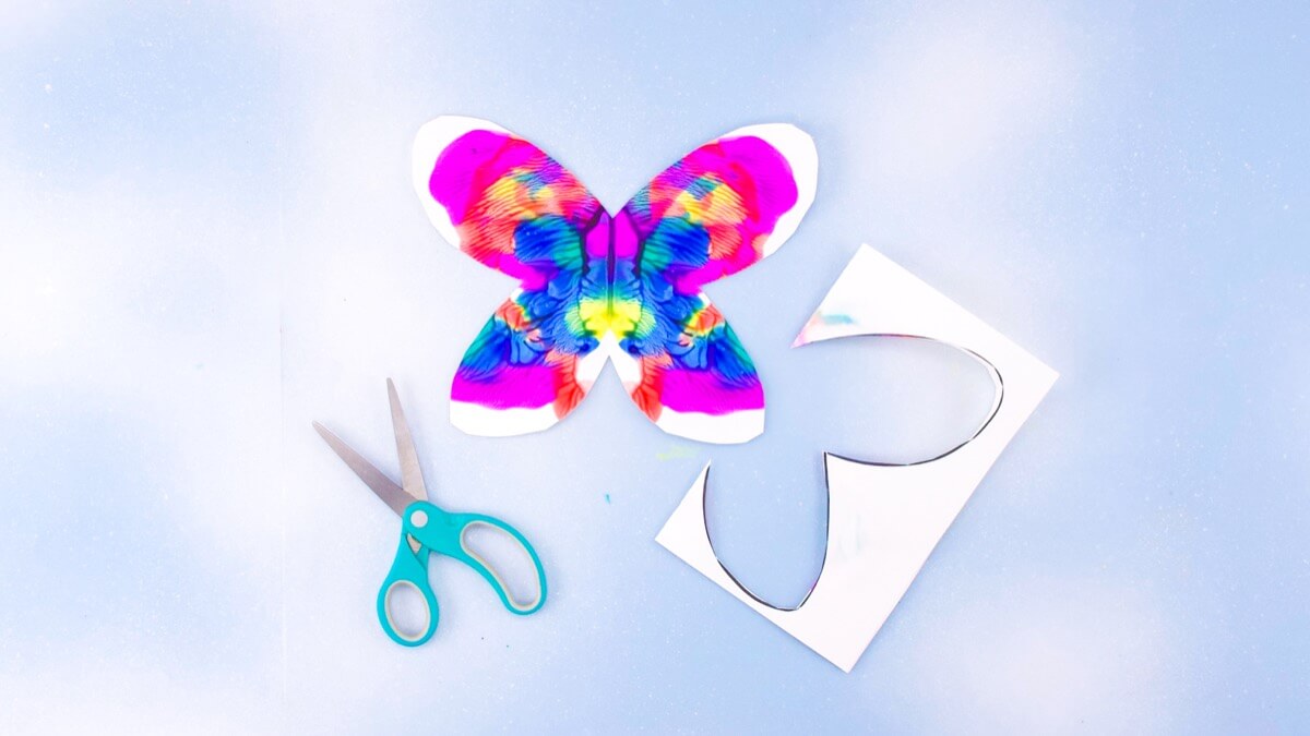 步骤6：一旦你的油漆干了，再把纸对折，剪下你之前画的蝴蝶翅膀形状。