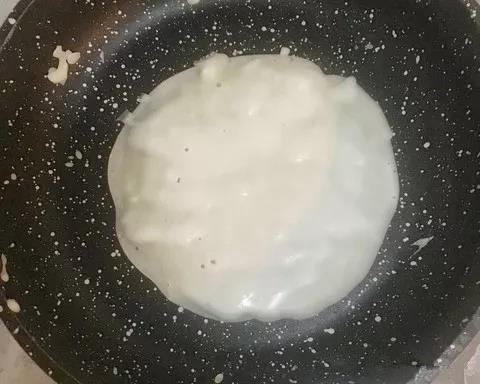第4步：锅内刷少许油，将面糊缓慢倒入，摊成圆形。饼底能推动时候翻面，两面煎熟，盛出备用。