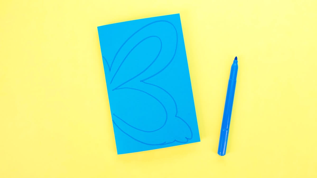 步骤2：将一张建筑纸对折并画出对称形状的一半。您可以画花、心、蝴蝶或相框。