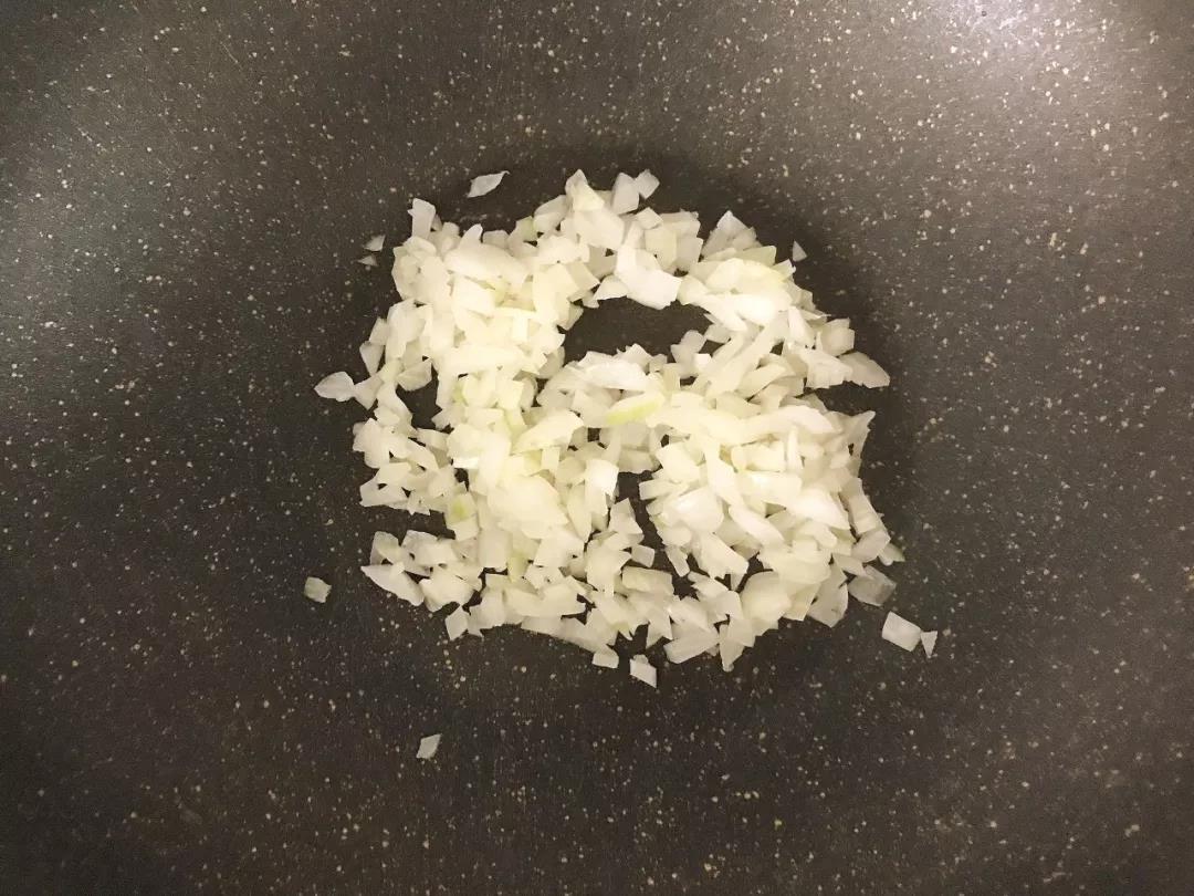 第3步：洋葱碎放入油锅炒香，拨至锅边。