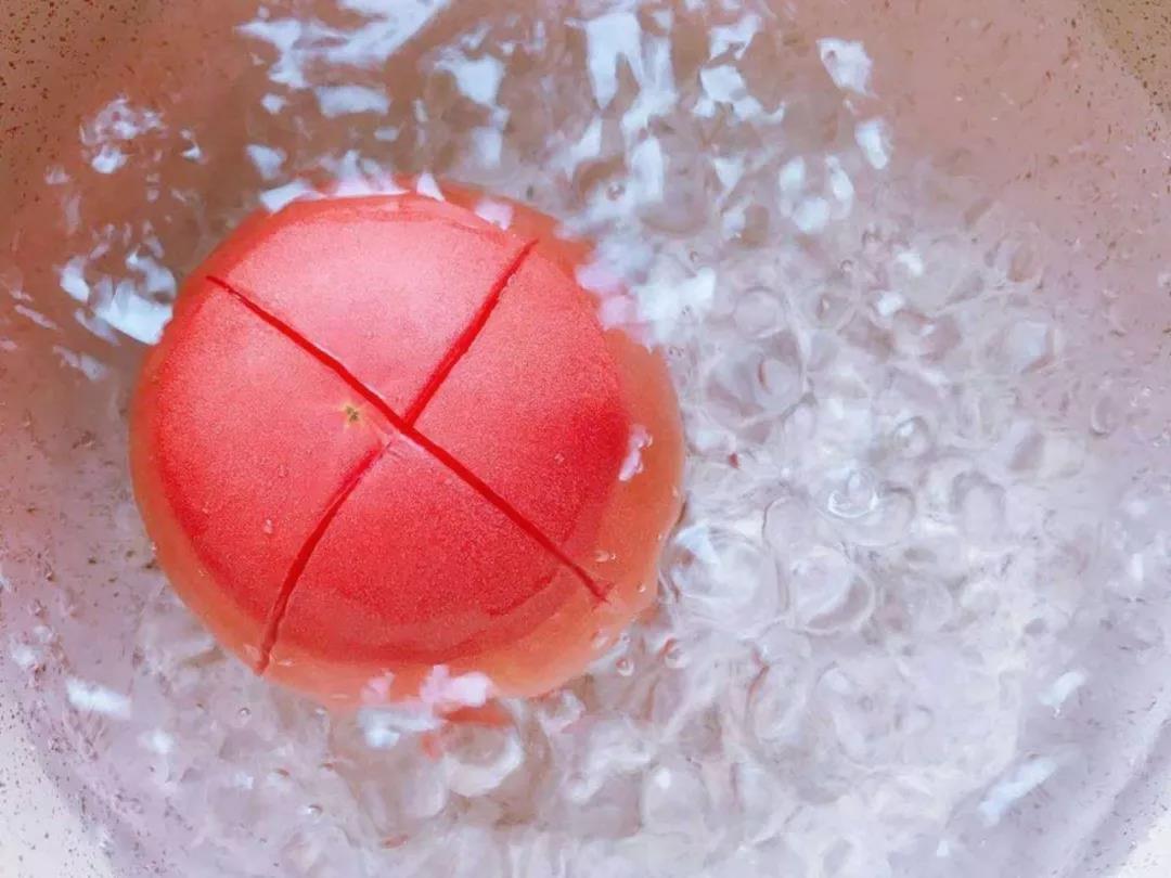 番茄顶部划十字，把番茄放在水里煮一分钟左右，煮至翘皮。