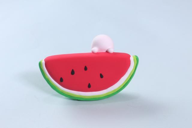 步骤7：先捏两个圆球粘在西瓜上，然后把小熊的身体粘在上面，如图所示。