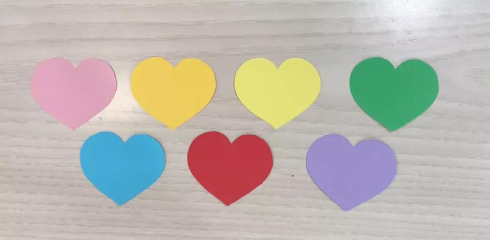 步骤1：用7种颜色的卡纸剪出7枚心形。