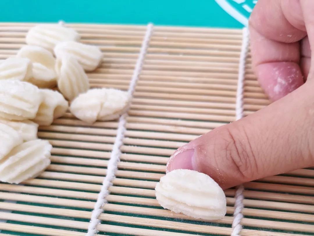 将小面团放在海苔竹卷帘上，用拇指轻轻向前一搓，成为海螺面疙瘩。