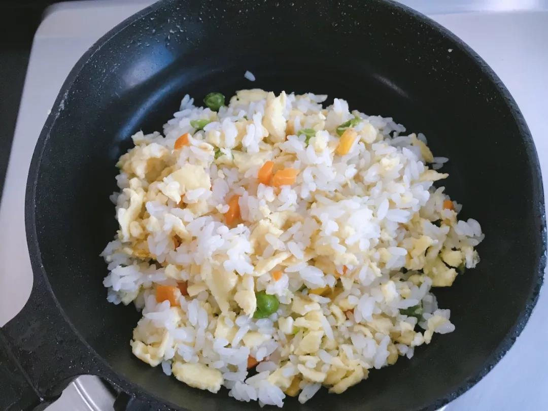 鸡蛋半凝固时倒入米饭继续翻炒均匀。