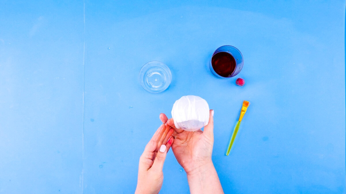 步骤5：为了制作水母的头部，将三个咖啡过滤纸叠在一起。用水弄湿过滤纸，并在 3 英寸到 4 英寸的球周围形成它们。我们使用的是透明的亚克力球。用手指抚平边缘。