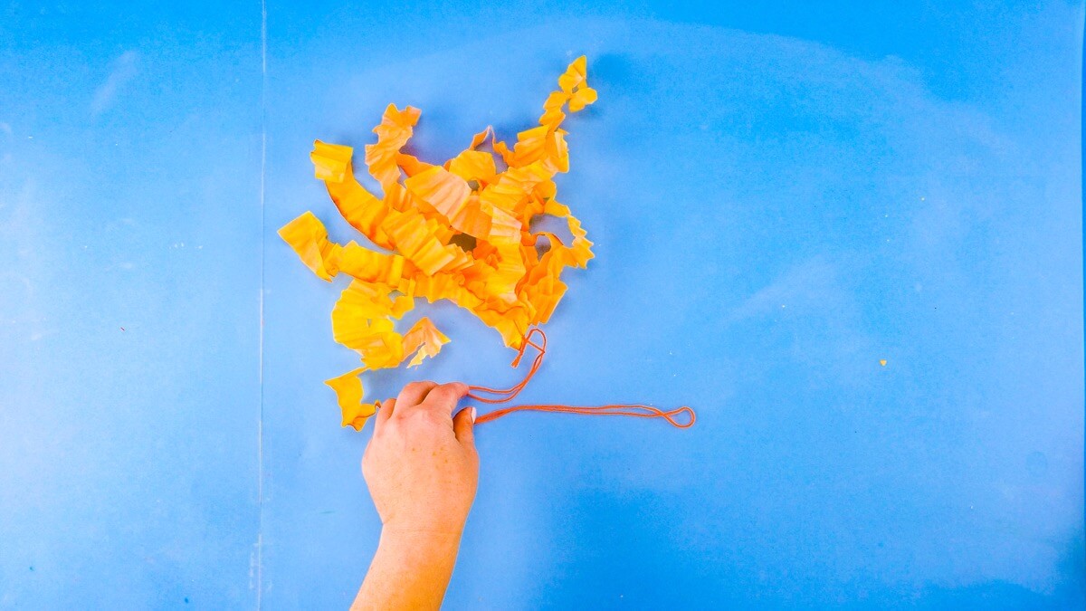 步骤11：将一段纱线穿过孔并用结将口腔臂系在一起。将纱线末端系起来，做成一个挂环。  