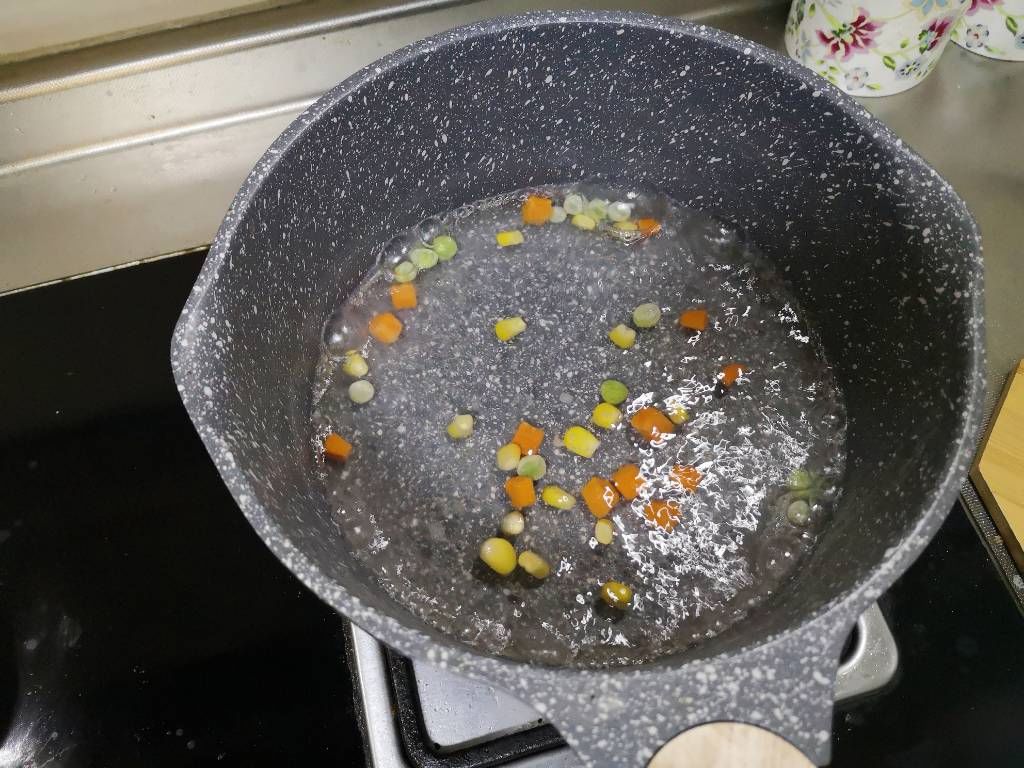 水开后把胡萝卜、豌豆、玉米焯至断生。