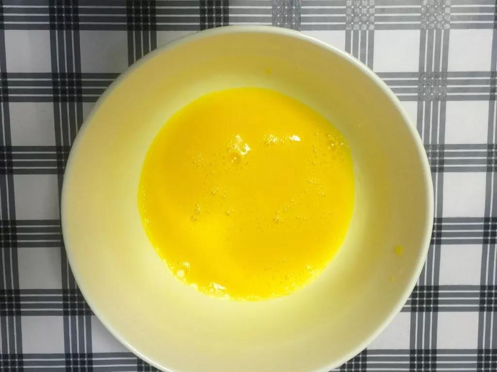 将鸡蛋磕入碗中并打散。