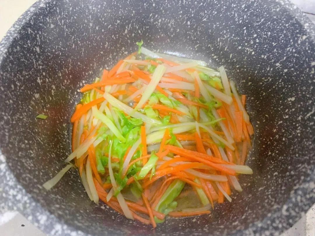 土豆丝捞出沥干水分，和胡萝卜丝、圆白菜一起入油锅翻炒。加少量水，盖盖焖煮2分钟。