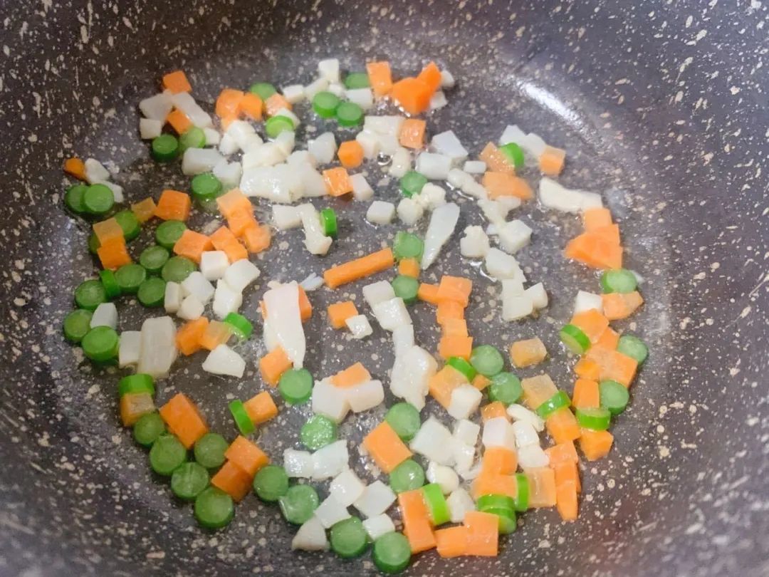 第5步：扇贝柱、胡萝卜、蒜苗入油锅翻炒。