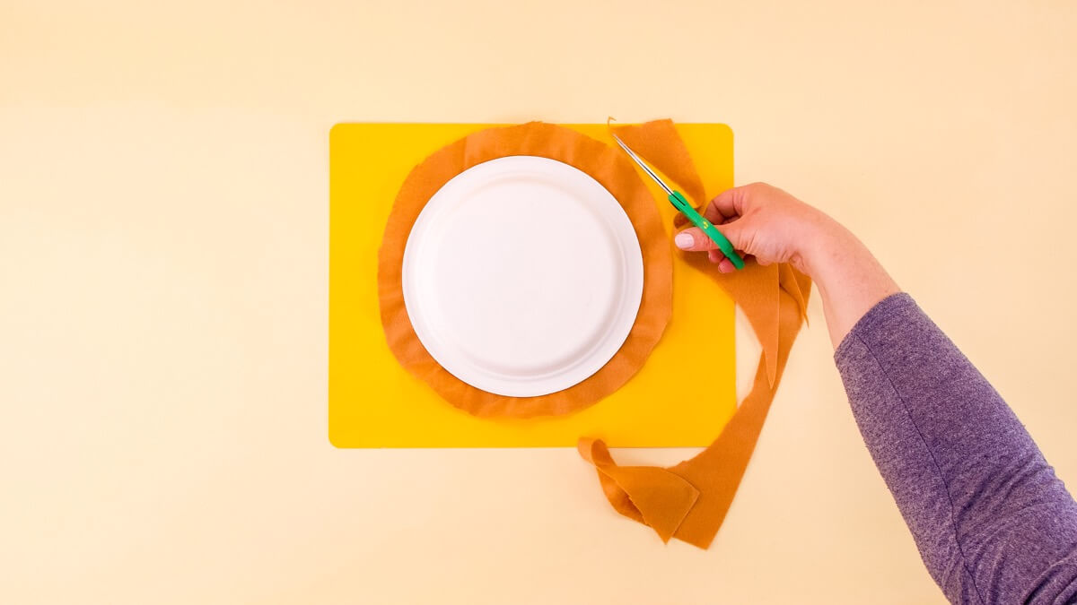 步骤4：将盘子翻过来，切割盘子周围的毛毡，在盘子边缘留下 3/4 英寸的毛毡边缘。