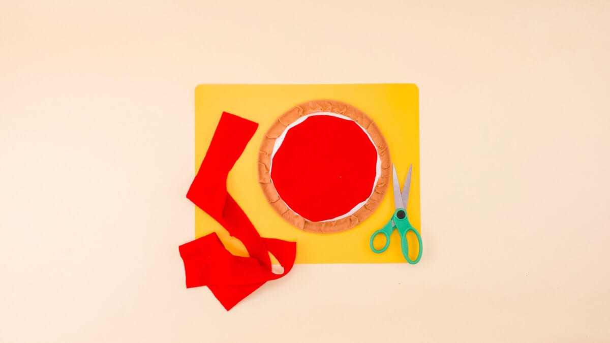 步骤6：要制作番茄酱，请使用记号笔将纸盘的内圈松散地描绘在红色毛毡上。然后剪出形状！ 