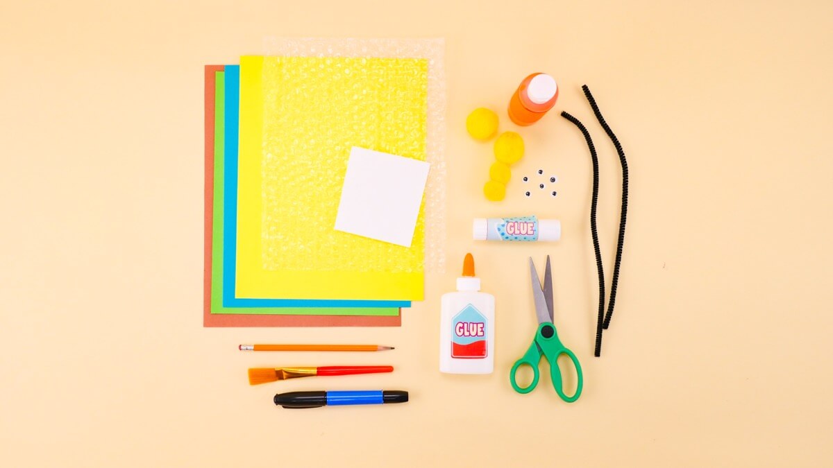 步骤1：泡沫包装、黄色和橙色颜料、卡纸——棕色、蓝色、黄色和绿色、黄色绒球、黑色扭扭棒、剪刀、工艺胶、胶棒、画笔——我们用了海绵画笔、蜡笔或记号笔、小白纸、眼睛