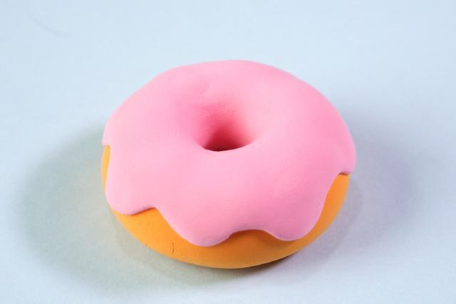 步骤3：用粉红色粘土做出不规则的片状覆盖在甜甜圈上，记得留出小洞。