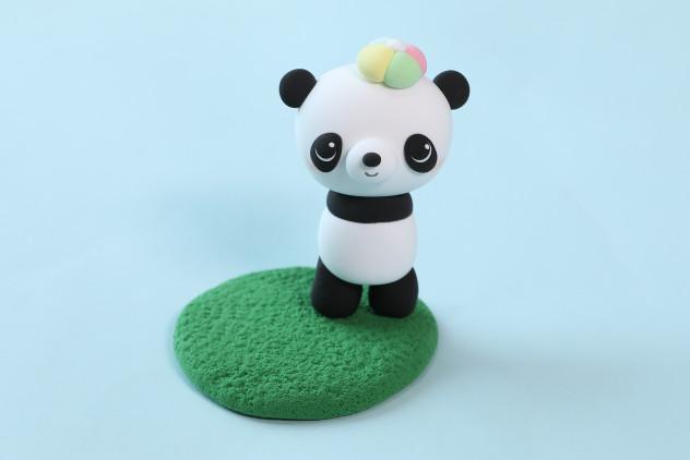 步骤8：用绿色粘土做一块草坪，让熊猫站在上面。