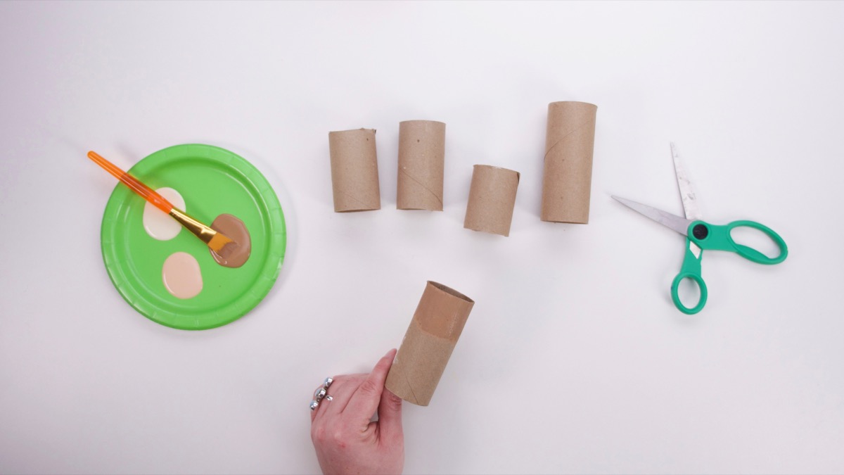 步骤2：用剪刀将纸管剪成不同的尺寸——成人长一些，儿童短一些。  在管子的 1/3 上涂上您家人的肤色，然后晾干。