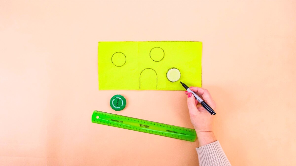 步骤3：接下来，在毛毡上的几个地方描绘你的小瓶盖，制作一些圆形窗户和门口的拱门。 