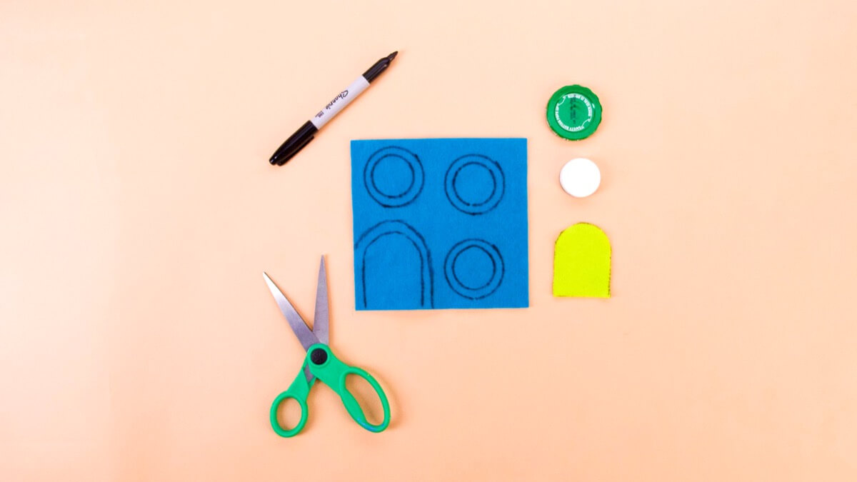 步骤5：要装饰您的门窗，请在您选择的新毛毡颜色上描绘大瓶盖和小瓶盖。您可以将切掉的门用作模板，方法是在毛毡上描绘并在其周围绘图。 