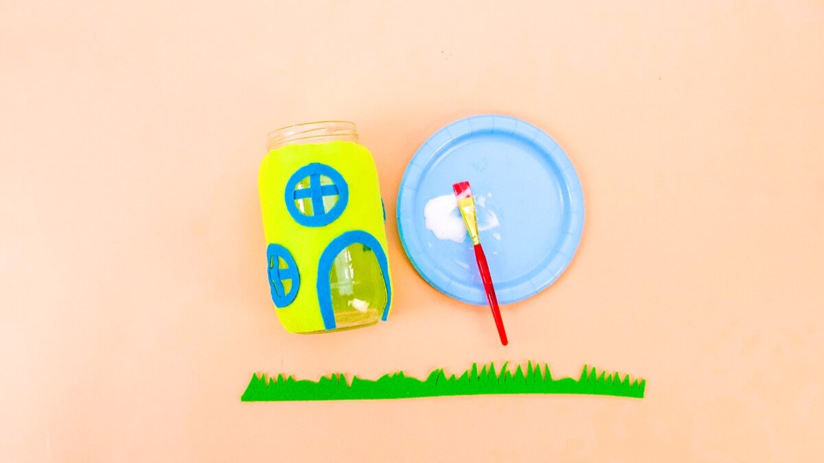 步骤13：剪一条足够长的绿色毡布，包裹在罐子的底部。修剪一些草纹理并将其粘贴到位。