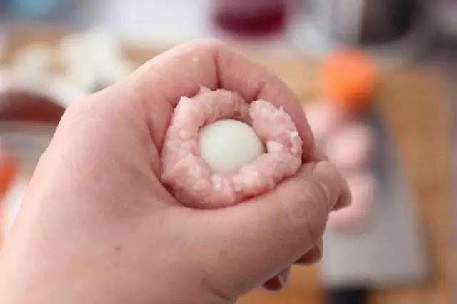 用虎口轻轻向上推肉糜，直到完全包住鹌鹑蛋，再搓圆。