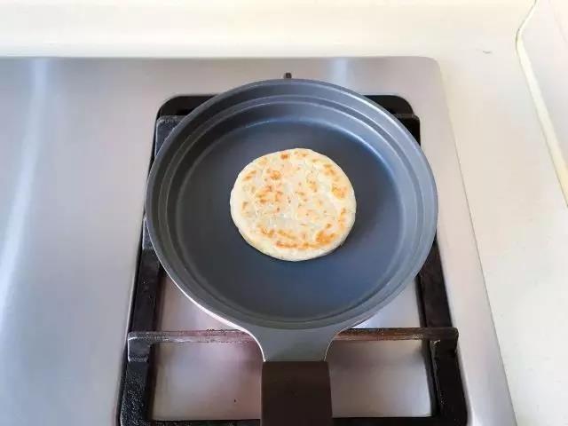 等一面定型后，翻面继续烘，能挪动之后开始慢慢的在锅里面晃动饼，这样周边就会收圆，边晃动边烘。饼一面金黄之后，再烘另一面，直到两面都金黄后出锅。