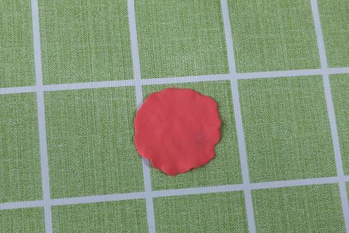 步骤7：下面开始做康乃馨，把大红色粘土压成不规则的圆片。