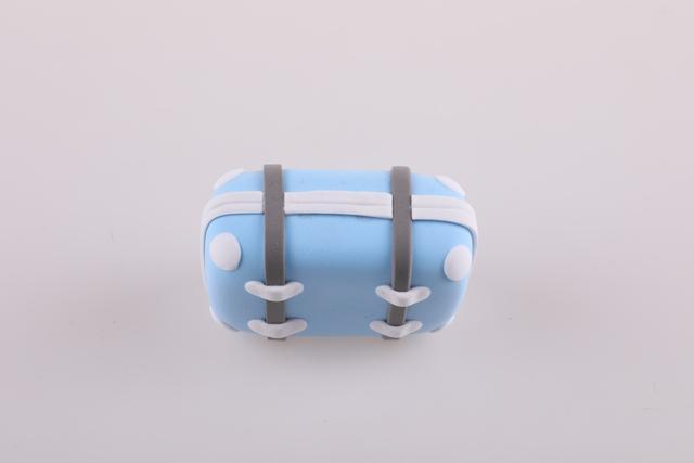 步骤5：然后用白色粘土做长方形细条粘在行李箱中间部位作为拉链。