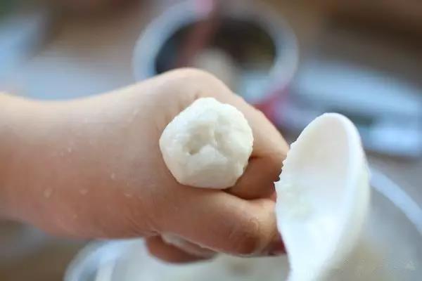 把鱼蓉放到手掌，从虎口挤出，用陶瓷小勺子，舀出一个丸子。