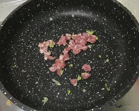 锅内倒少许油，放葱炒香后加牛肉翻炒。