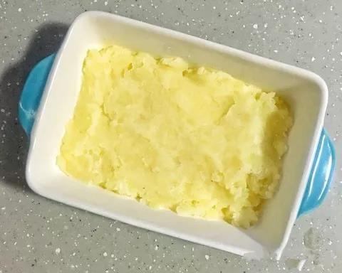 将土豆泥均匀的铺在烤碗底，用勺背整平。