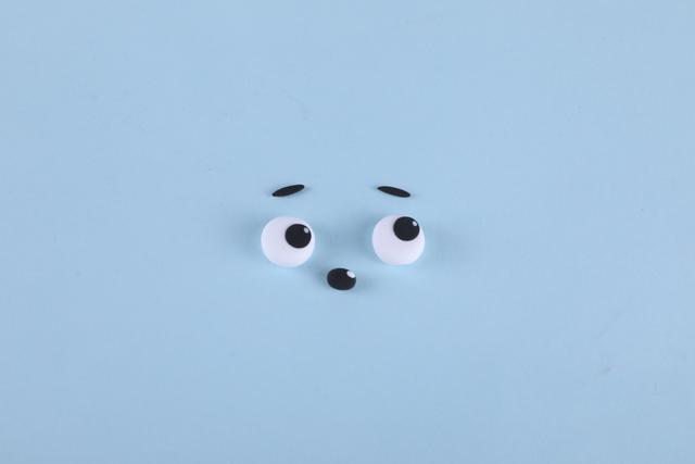 步骤2：然后用黑色粘土做出两条眉毛，小鼻子，再用黑白色粘土做出眼睛。