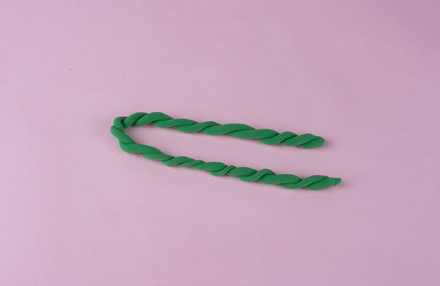 步骤1：首先我们来做花环，先用绿色粘土揉两根细条，然后把它们拧成一根