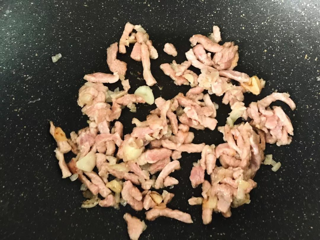 第4步：猪肉丝放入锅中炒至变色，拨至锅边。